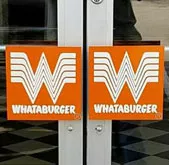 A black geometric door handle on a glass door, featuring the Whataburger logo