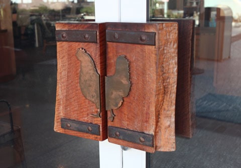 Rustic wooden door handles with rooster silhouettes on glass door